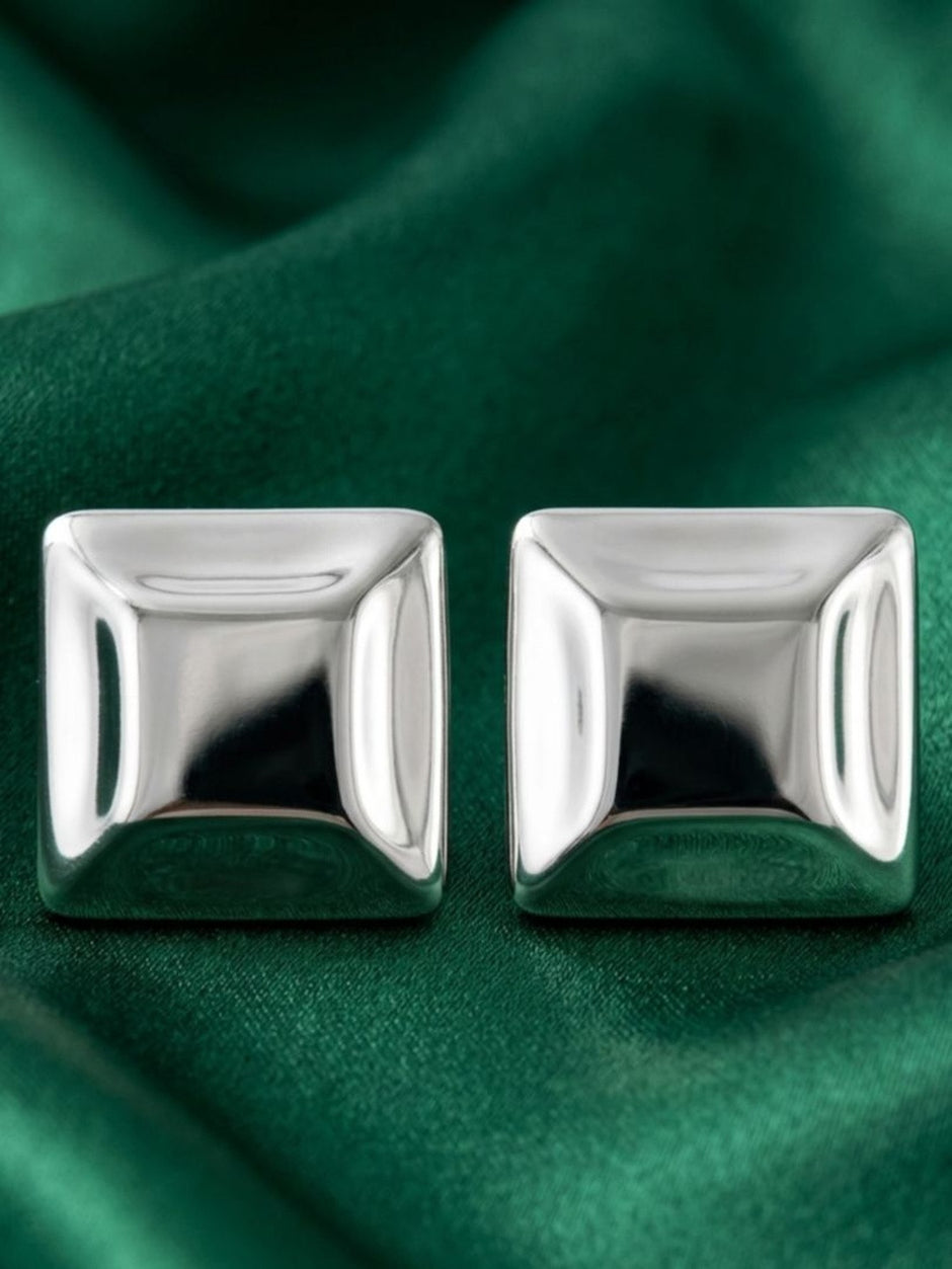Pair of polished silver square stud earrings displayed side by side on green satin fabric