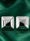 Pair of polished silver square stud earrings displayed side by side on green satin fabric