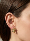 Gold ball and bar drop earring worn on the ear of a woman with dark hair pulled back