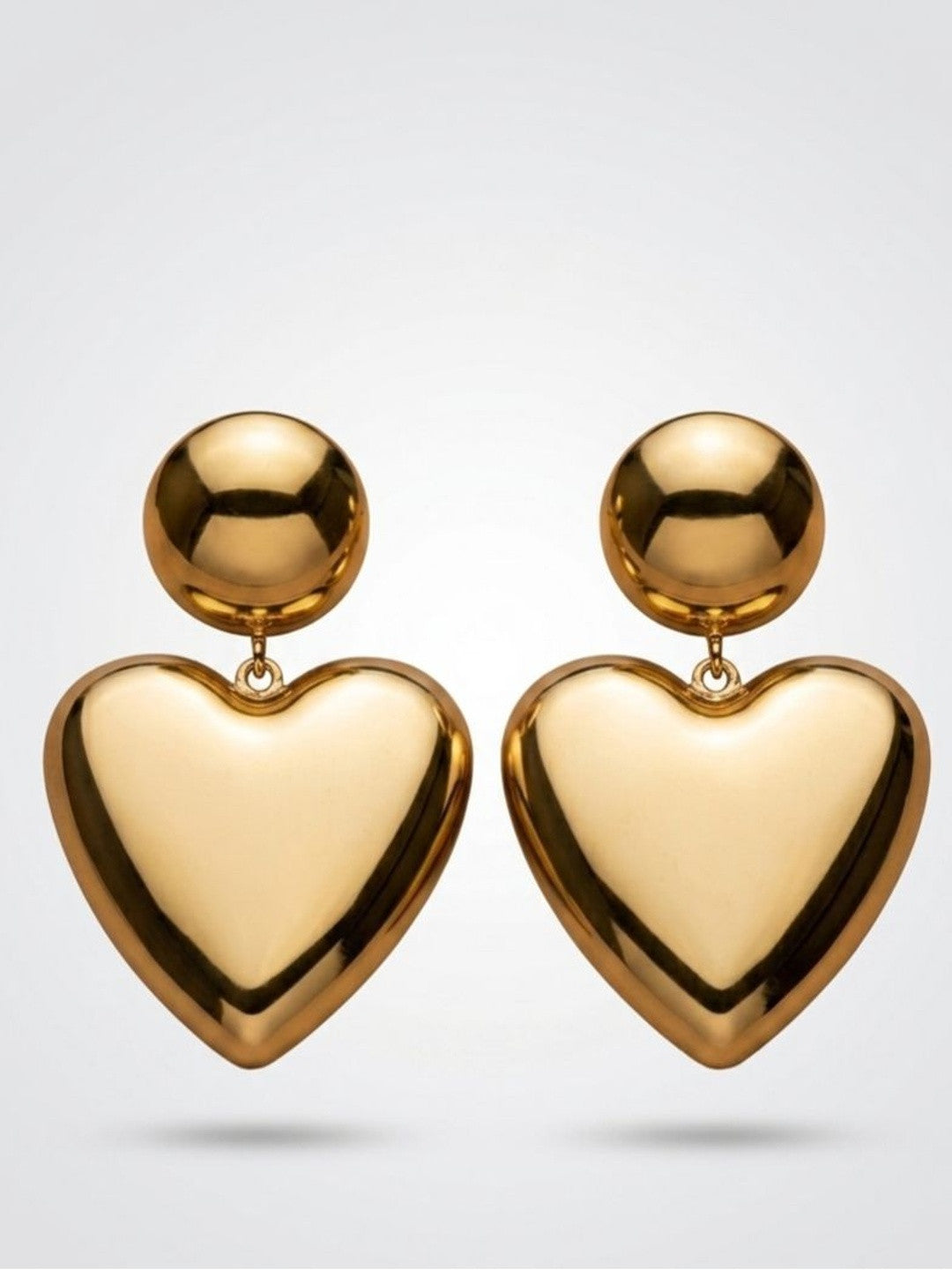 Gold-plated oversized heart drop earrings with ball studs on a white background