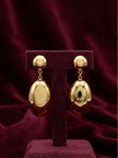 Pair of gold-plated oval drop earrings displayed on a burgundy velvet jewellery stand