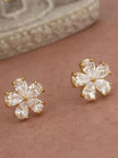 Pair of gold-plated five-petal cubic zirconia flower stud earrings on a pink surface