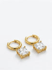 Pair of gold-plated huggie hoop earrings with square cubic zirconia charm pendants on white background