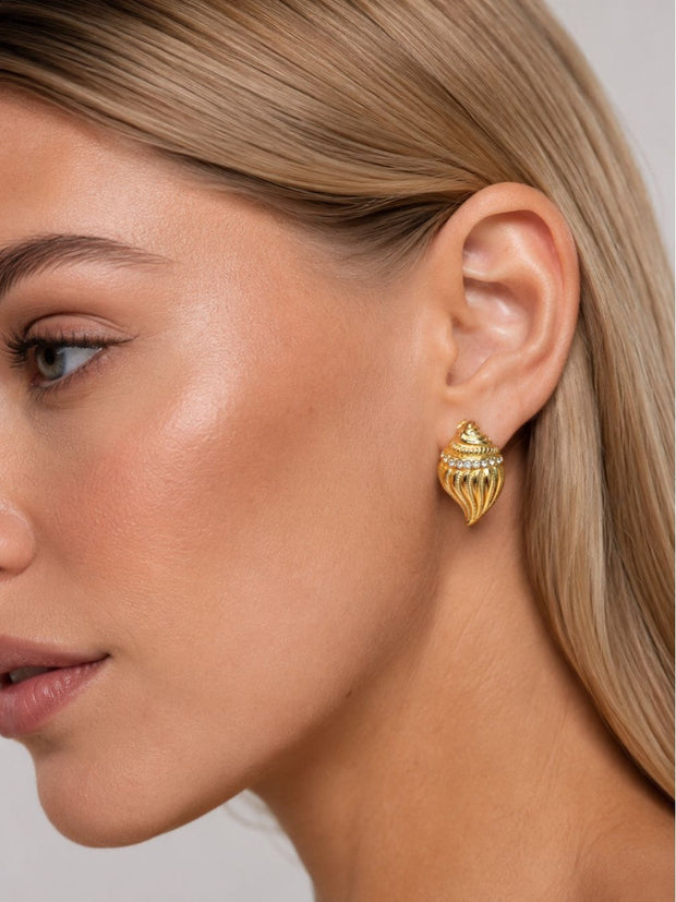 Woman wearing gold conch shell crystal stud earring on right ear, side profile view