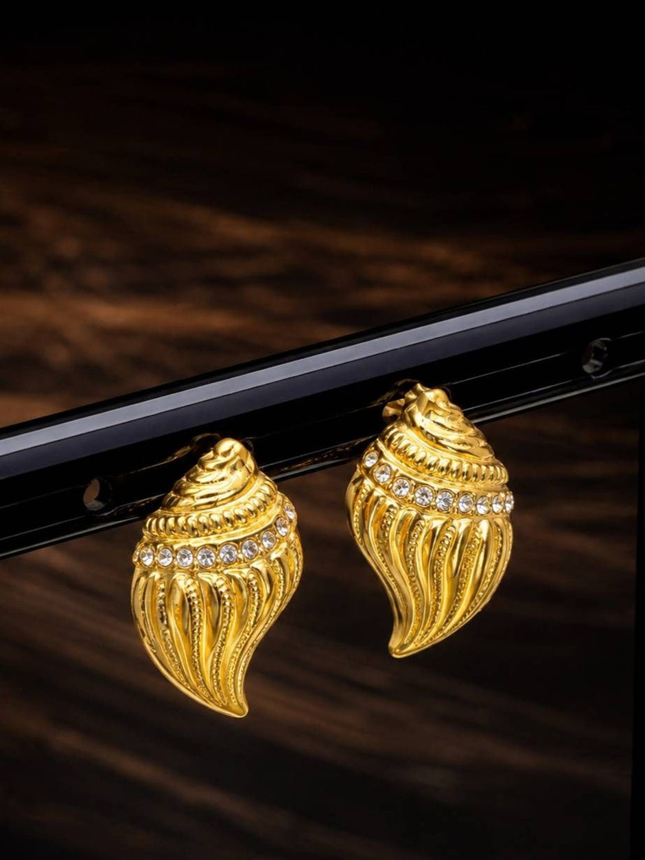 Close-up of gold conch shell stud earrings with crystal row hanging on black rack