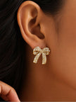 Close-up of gold rhinestone bow stud earring worn on a model's right ear