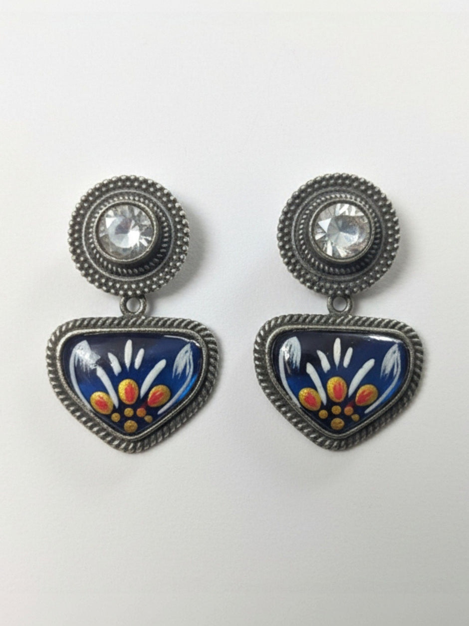 Flat lay of both meenakari drop stud earrings on white background showing blue, white, yellow and orange enamel floral design and rope-edge border