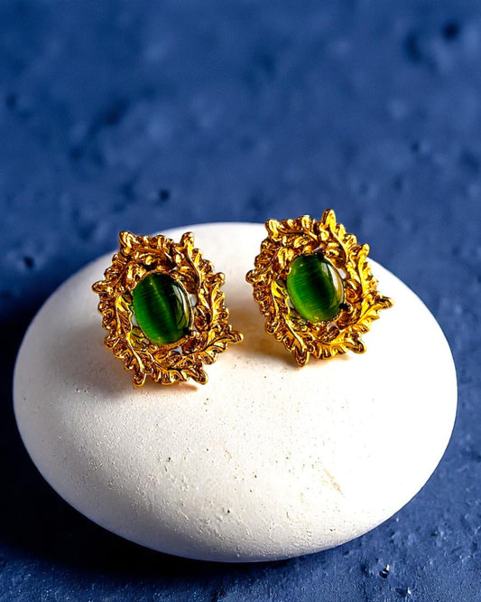 Gold plated stud earrings with green gemstone center displayed on white stone – Glampouch jewelry