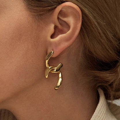 Gold abstract knot earrings worn by woman, bold modern statement jewelry for everyday and party look
