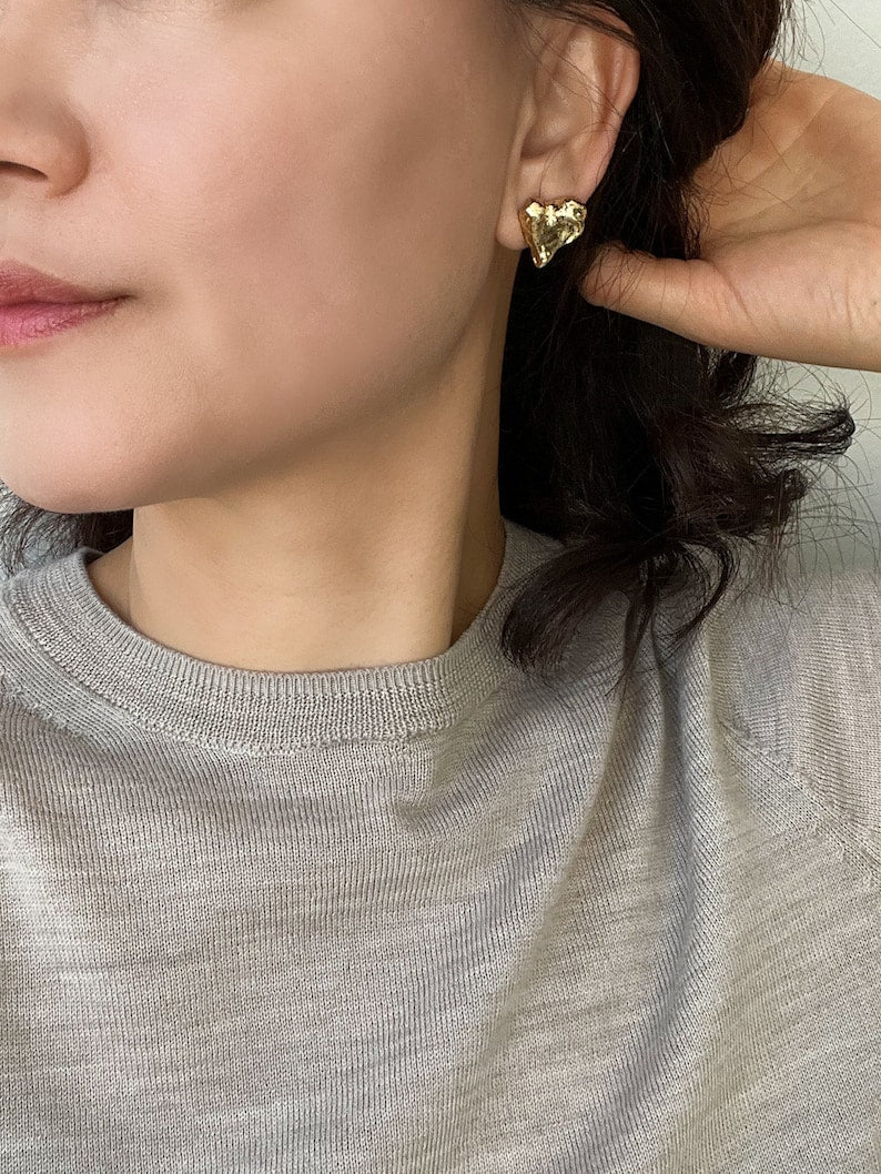 Textured gold heart stud earrings styled on woman, modern chic jewellery for everyday wear and romantic statement looks