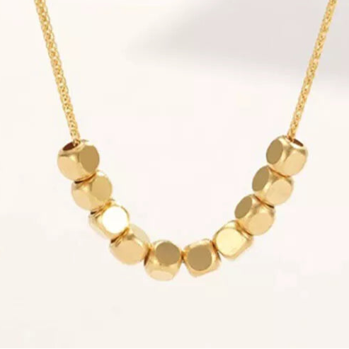 Minimalist gold necklace with polished cube beads, modern geometric design on delicate chain.