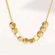 Minimalist gold necklace with polished cube beads, modern geometric design on delicate chain.